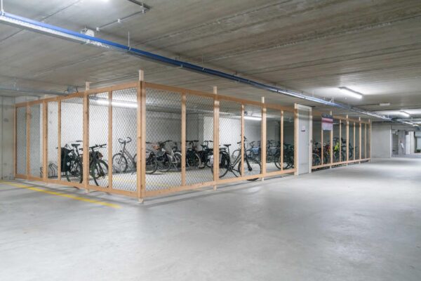 Afgesloten fietsenstalling met houten frame en gaaswerk in een ondergrondse parkeergarage aan de De Bruyn Kopsstraat.